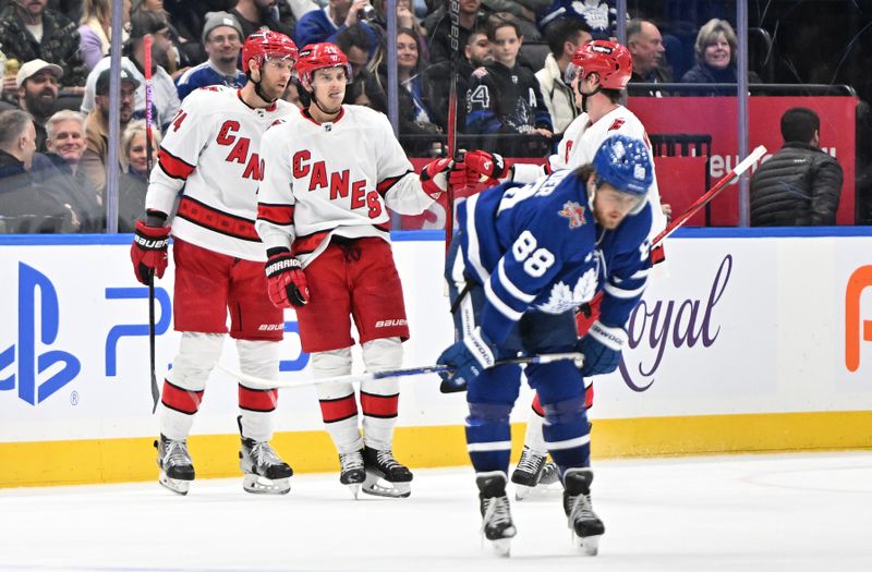 Dec 30, 2023; Toronto, Ontario, CAN; Carolina Hurricanes forward Sebastian Aho (20) celebrates with forward Jordan Staal (11) and defenseman Jaccob Slavin (74) after scoring an empty net goal as Toronto Maple Leafs forward 
William Nylander (88) skates away in the third period at Scotiabank Arena. Mandatory Credit: Dan Hamilton-USA TODAY Sports