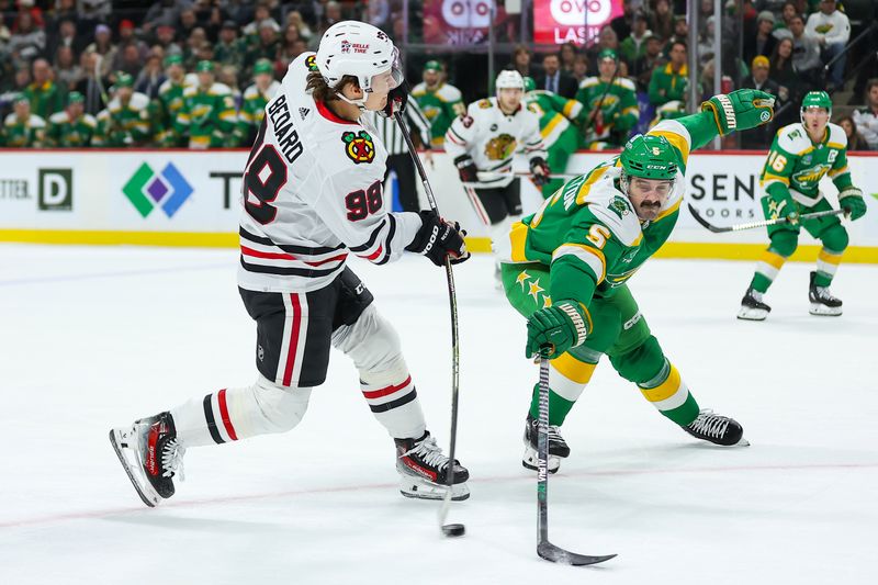 Dec 3, 2023; Saint Paul, Minnesota, USA; Chicago Blackhawks center Connor Bedard (98) shoots against Minnesota Wild defenseman Jake Middleton (5) during the first period at Xcel Energy Center. Mandatory Credit: Matt Krohn-USA TODAY Sports