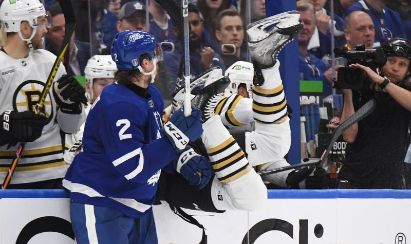 May 2, 2024; Toronto, Ontario, CAN;   Boston Bruins forward Justin Brazeau (55) flips over the boards of the Bruins bench after missing a bodycheck on Toronto Maple Leafs defenseman Simon Benoit (2) in the first period in game six of the first round of the 2024 Stanley Cup Playoffs at Scotiabank Arena. Mandatory Credit: Dan Hamilton-USA TODAY Sports