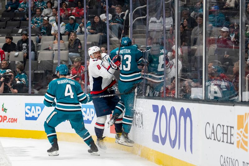 Nov 27, 2023; San Jose, California, USA; San Jose Sharks defenseman Nikita Okhotiuk (83) is checked into the boards by Washington Capitals left wing Alex Ovechkin (8) during the third period at SAP Center at San Jose. Mandatory Credit: Neville E. Guard-USA TODAY Sports