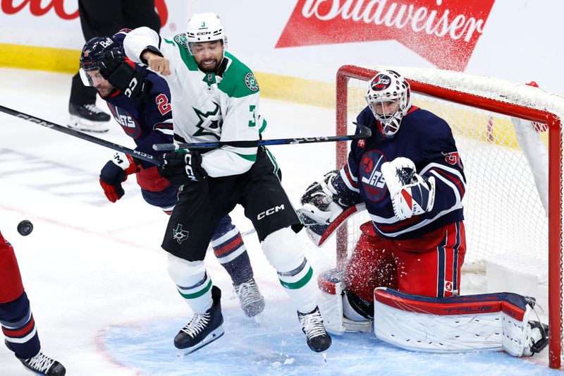 Nov 9, 2024; Winnipeg, Manitoba, CAN;Dallas Stars defenseman Mathew Dumba (3) loses a glove while screening Winnipeg Jets goaltender Connor Hellebuyck (37) in the third period at Canada Life Centre. Mandatory Credit: James Carey Lauder-Imagn Images