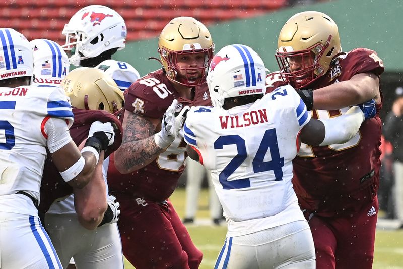 Dec 28, 2023; Boston, MA, USA; Boston College Eagles offensive lineman Logan Taylor (65) and offensive lineman Kevin Cline (79) team up on Southern Methodist Mustangs linebacker Kobe Wilson (24) during the second half at Fenway Park. Mandatory Credit: Eric Canha-USA TODAY Sports