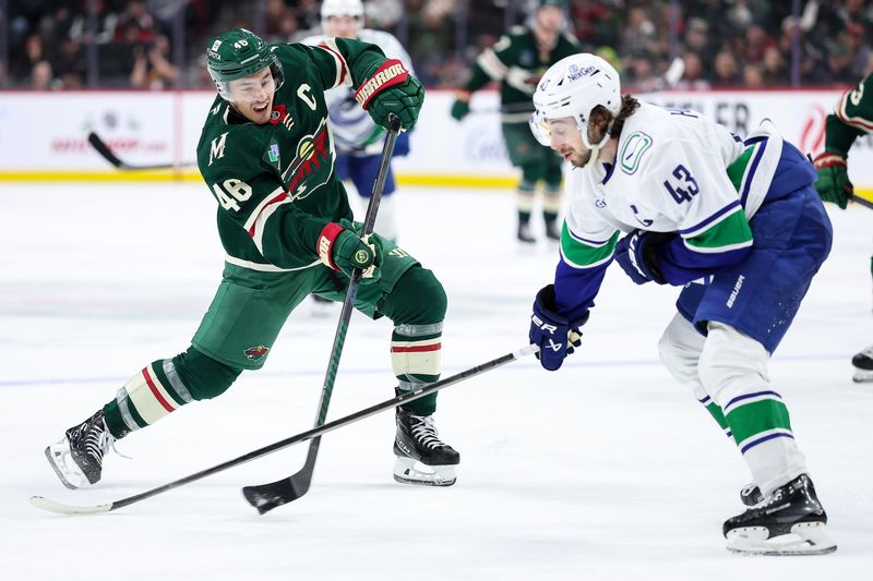 Dec 3, 2024; Saint Paul, Minnesota, USA; Minnesota Wild defenseman Jared Spurgeon (46) shoots as Vancouver Canucks defenseman Quinn Hughes (43) defends during the third period at Xcel Energy Center. Mandatory Credit: Matt Krohn-Imagn Images