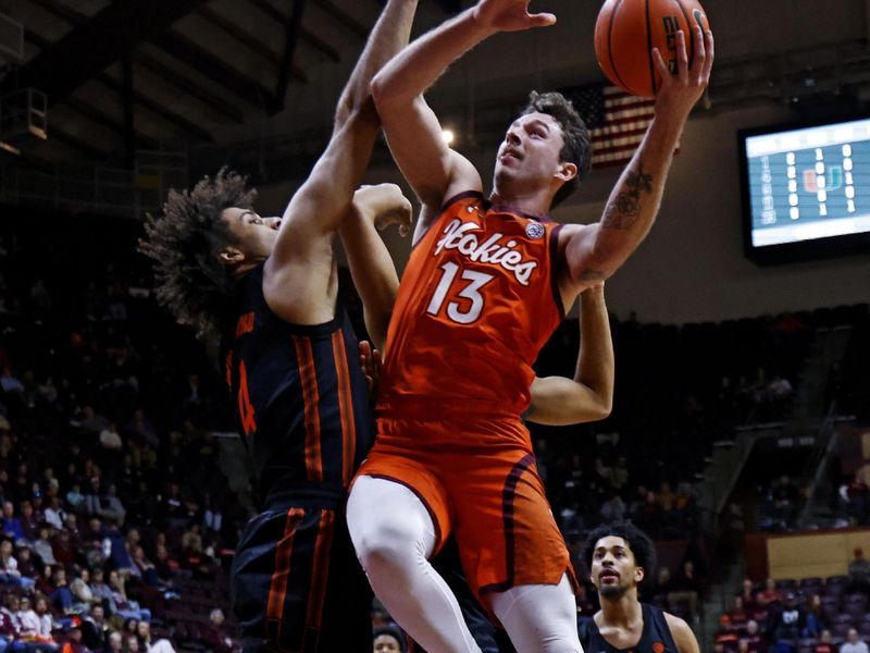 Jan 4, 2025; Blacksburg, Virginia, USA; Virginia Tech Hokies forward Ben Burnham (13) shoots the ball against Miami Hurricanes forward Isaiah Johnson-Arigu (4) during the first half at Cassell Coliseum. Mandatory Credit: Peter Casey-Imagn Images