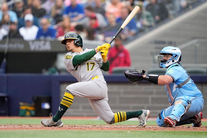 Jun 1, 2025; Toronto, Ontario, CAN; Oakland Athletics second baseman Luis Urias (17) hits an RBI double against the Toronto Blue Jays during the fifth inning at Rogers Centre. Mandatory Credit: John E. Sokolowski-Imagn Images