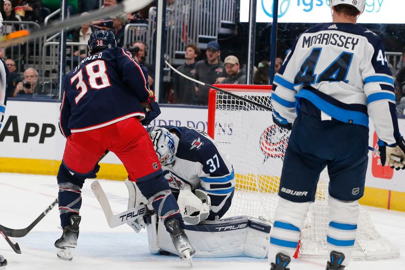 Mar 17, 2024; Columbus, Ohio, USA; Winnipeg Jets goalie Connor Hellebuyck (37) makes a save as Columbus Blue Jackets center Boone Jenner (38) looks for a rebound during the second period at Nationwide Arena. Mandatory Credit: Russell LaBounty-USA TODAY Sports