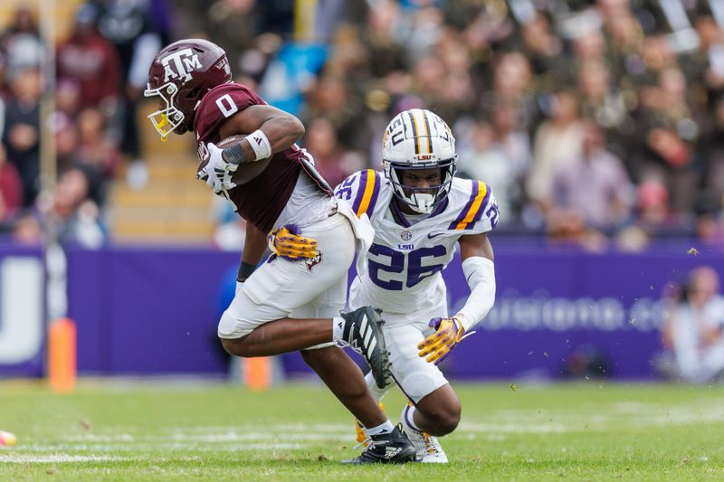 Nov 25, 2023; Baton Rouge, Louisiana, USA;  Texas A&M Aggies wide receiver Ainias Smith (0) breaks the tackle of LSU Tigers cornerback Ashton Stamps (26) during the second half at Tiger Stadium. Mandatory Credit: Stephen Lew-USA TODAY Sports