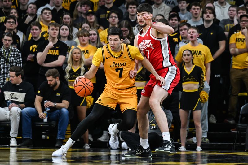 Feb 25, 2026; Iowa City, Iowa, USA; Iowa Hawkeyes forward Alvaro Folgueiras (7) controls the ball as Ohio State Buckeyes center Ivan Njegovan (7) defends during the first half at Carver-Hawkeye Arena. Mandatory Credit: Jeffrey Becker-Imagn Images