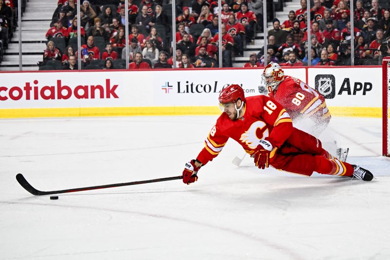 Jan 16, 2024; Calgary, Alberta, CAN; Calgary Flames left wing A.J. Greer (18) stretches for the puck during the second period in a game against the Arizona Coyotes at Scotiabank Saddledome. Mandatory Credit: Brett Holmes-USA TODAY Sports