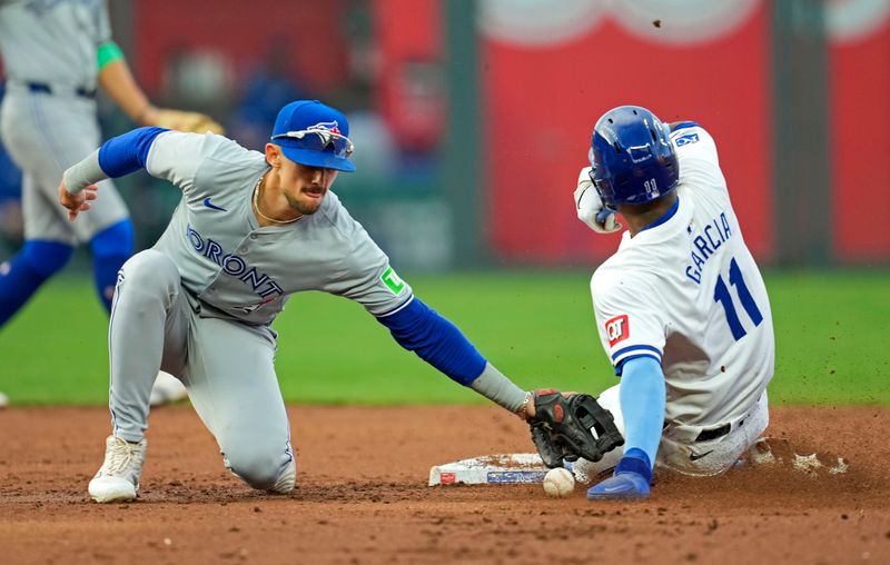 Apr 24, 2024; Kansas City, Missouri, USA; Kansas City Royals third base Maikel Garcia (11) steals second base as Toronto Blue Jays second base Cavan Biggio (8) drops the ball during the second inning at Kauffman Stadium. Mandatory Credit: Jay Biggerstaff-USA TODAY Sports