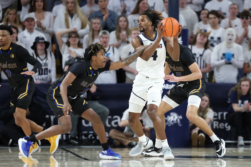 Jan 30, 2024; Logan, Utah, USA; San Jose State Spartans forward Christian Wise (left) reaches for the the ball held by Utah State Aggies guard Josh Uduje (right) during the first half at Dee Glen Smith Spectrum. Mandatory Credit: Rob Gray-USA TODAY Sports