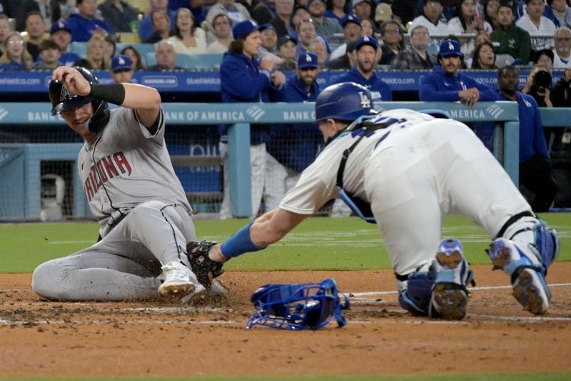 May 20, 2024; Los Angeles, California, USA;  Arizona Diamondbacks shortstop Kevin Newman (18) beats the tag by Los Angeles Dodgers catcher Will Smith (16) as he scores on a single by designated hitter Joc Pederson (3) in the third inning at Dodger Stadium. Mandatory Credit: Jayne Kamin-Oncea-USA TODAY Sports