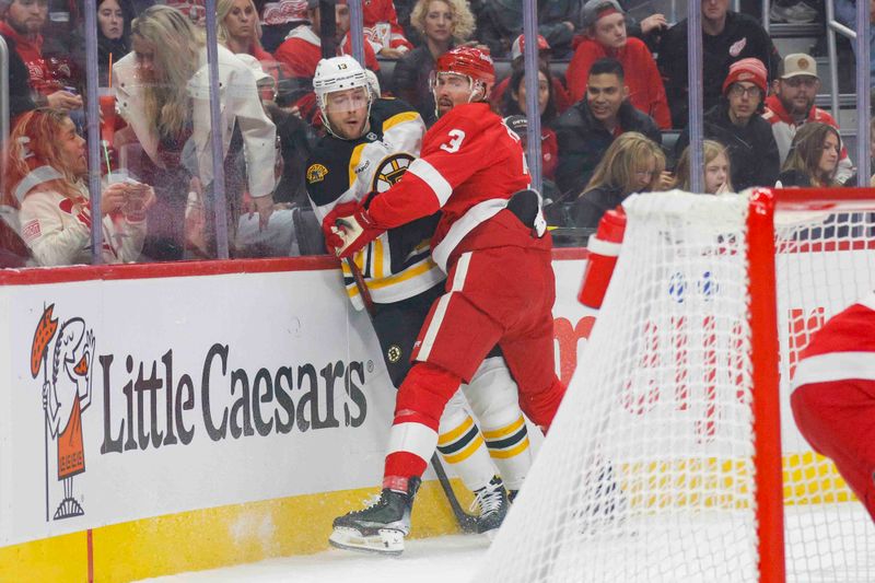 Nov 23, 2024; Detroit, Michigan, USA; Detroit Red Wings defenseman Justin Holl (3) checks Boston Bruins center Charlie Coyle (13) into the boards during the first period at Little Caesars Arena. Mandatory Credit: Brian Bradshaw Sevald-Imagn Images