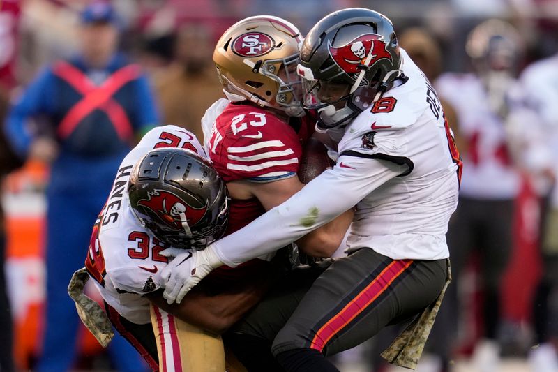 Tampa Bay Buccaneers safety Josh Hayes, left, and linebacker SirVocea Dennis, right, tackle San Francisco 49ers running back Christian McCaffrey during the second half of an NFL football game Sunday, Nov. 19, 2023, in Santa Clara, Calif. (AP Photo/Godofredo A. Vásquez)