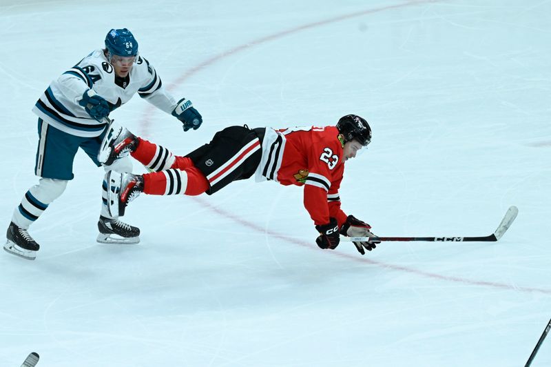 Jan 16, 2024; Chicago, Illinois, USA; Chicago Blackhawks center Philipp Kurashev (23) and San Jose Sharks right wing Mitchell Russell (64) chase the puck during the second period at United Center. Mandatory Credit: Matt Marton-USA TODAY Sports