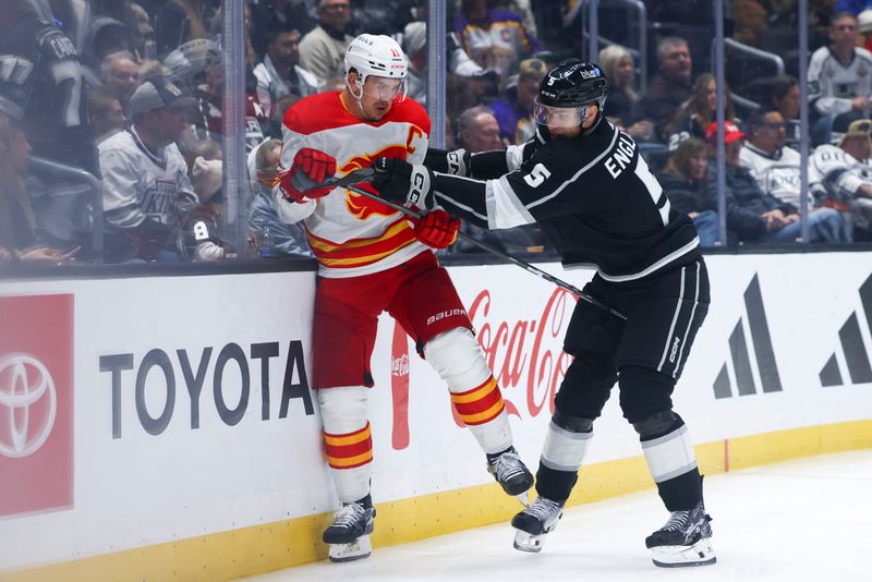 Dec 23, 2023; Los Angeles, California, USA; Los Angeles Kings defenseman Andreas Englund (5) checks Calgary Flames center Mikael Backlund (11) into the boards during the third period of a game at Crypto.com Arena. Mandatory Credit: Jessica Alcheh-USA TODAY Sports