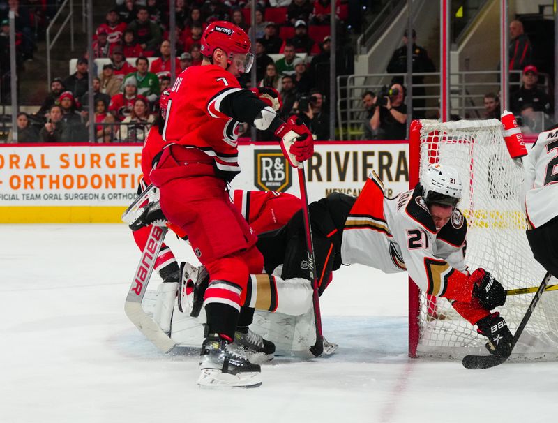 Jan 11, 2024; Raleigh, North Carolina, USA; Anaheim Ducks center Isac Lundestrom (21) is checked into Carolina Hurricanes goaltender Pyotr Kochetkov (52) by defenseman Dmitry Orlov (7) during the second period t PNC Arena. Mandatory Credit: James Guillory-USA TODAY Sports