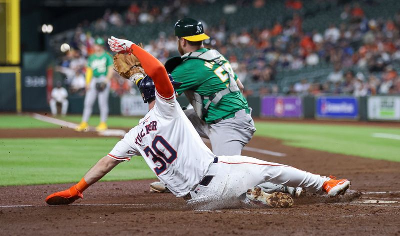 May 16, 2024; Houston, Texas, USA; Houston Astros right fielder Kyle Tucker (30) slides to score a run as Oakland Athletics catcher Kyle McCann (52) fields the throw during the fourth inning at Minute Maid Park. Mandatory Credit: Troy Taormina-USA TODAY Sports