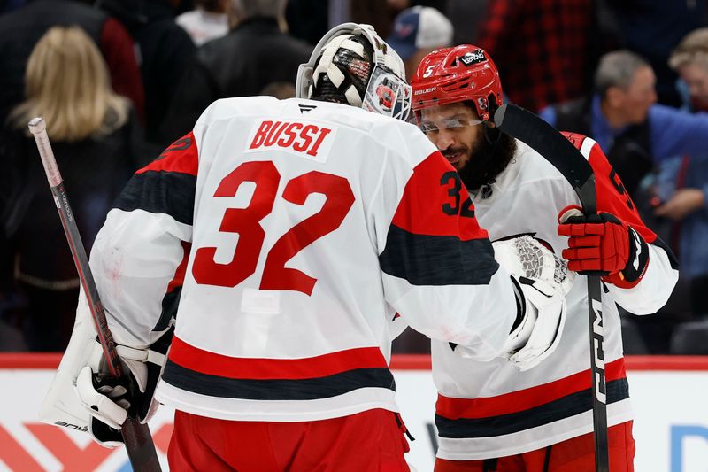 Dec 11, 2025; Washington, District of Columbia, USA; Carolina Hurricanes goaltender Brandon Bussi (32) celebrates with Hurricanes defenseman Jalen Chatfield (5) after a shootout against the Washington Capitals at Capital One Arena. Mandatory Credit: Geoff Burke-Imagn Images