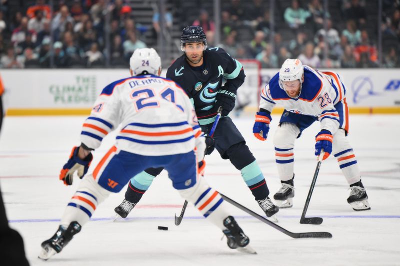 Oct 2, 2024; Seattle, Washington, USA; Seattle Kraken right wing Jordan Eberle (7) advances the puck while defended by Edmonton Oilers right wing Connor Brown (28) and defenseman Travis Dermott (24) during the first period at Climate Pledge Arena. Mandatory Credit: Steven Bisig-Imagn Images