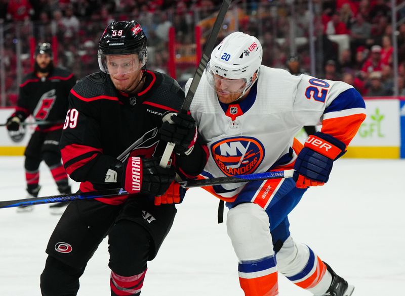 Apr 30, 2024; Raleigh, North Carolina, USA; Carolina Hurricanes center Jake Guentzel (59) and New York Islanders right wing Hudson Fasching (20) battle for position during the first period in game five of the first round of the 2024 Stanley Cup Playoffs at PNC Arena. Mandatory Credit: James Guillory-USA TODAY Sports