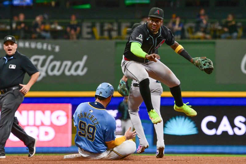 Sep 22, 2024; Milwaukee, Wisconsin, USA; Arizona Diamondbacks shortstop Geraldo Perdomo (2) completes a double play after forcing out Milwaukee Brewers catcher Gary Sanchez (99) in the seventh inning at American Family Field. Mandatory Credit: Benny Sieu-Imagn Images