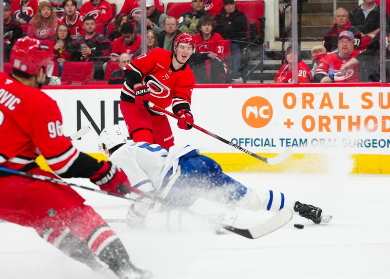 Apr 13, 2025; Raleigh, North Carolina, USA;  Carolina Hurricanes right wing Andrei Svechnikov (37) slips the puck past Toronto Maple Leafs defenseman Philippe Myers (51) during the third period at Lenovo Center. Mandatory Credit: James Guillory-Imagn Images