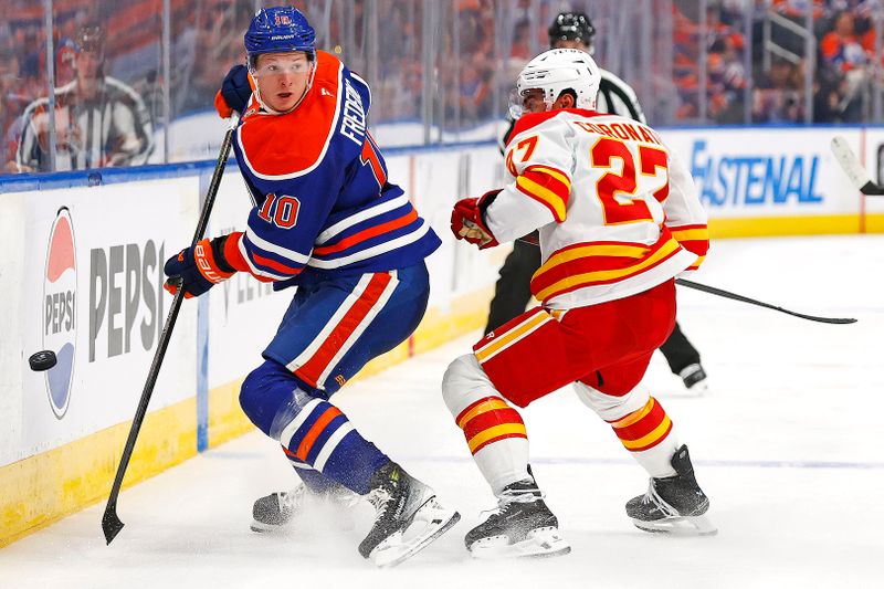 Oct 8, 2025; Edmonton, Alberta, CAN; Edmonton Oilers forward Trent Frederic (10) and Calgary Flames forward Matt Coronato (27) battle along the boards for a loose puck during the second period at Rogers Place. Mandatory Credit: Perry Nelson-Imagn Images