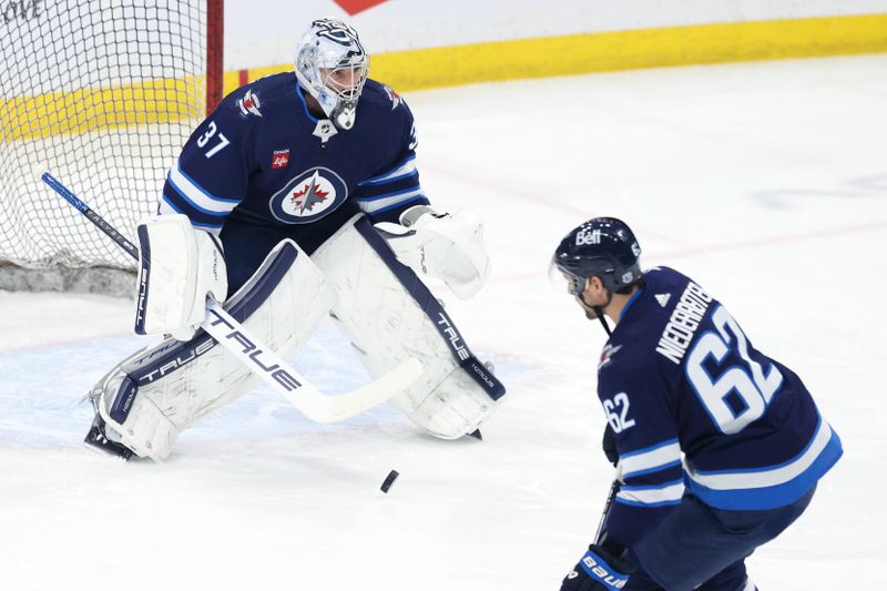 Mar 11, 2024; Winnipeg, Manitoba, CAN; Winnipeg Jets goaltender Connor Hellebuyck (37) blocks a shot by Winnipeg Jets right wing Nino Niederreiter (62) in warm up before a game against the Washington Capitals at Canada Life Centre. Mandatory Credit: James Carey Lauder-USA TODAY Sports