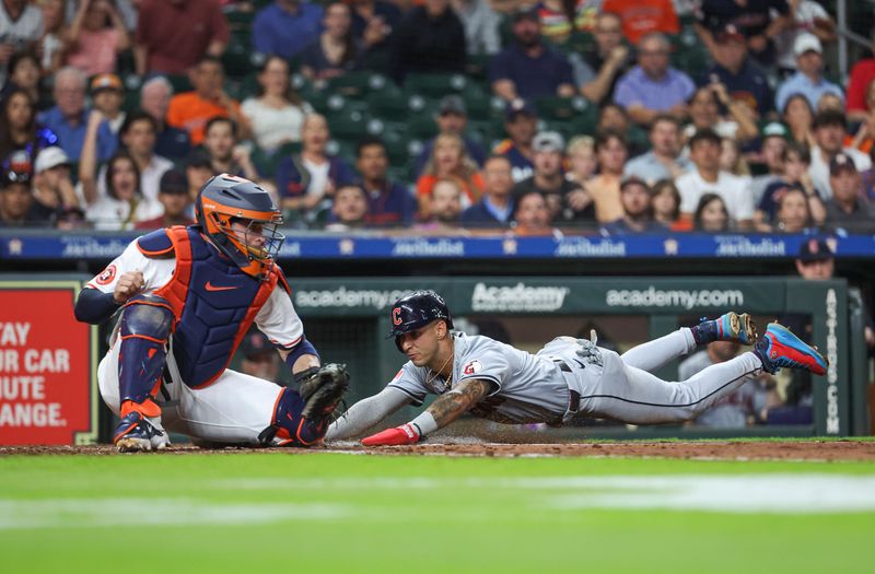 May 1, 2024; Houston, Texas, USA;  Cleveland Guardians shortstop Brayan Rocchio (4) slides past Houston Astros catcher Victor Caratini (17) to score a run during the fifth inning at Minute Maid Park. Mandatory Credit: Troy Taormina-USA TODAY Sports