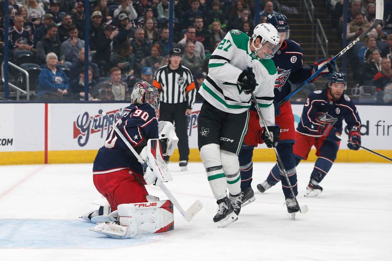 Feb 25, 2025; Columbus, Ohio, USA; Columbus Blue Jackets goalie Elvis Merzlikins (90) makes a save through the screen of Dallas Stars left wing Mason Marchment (27) during the first period at Nationwide Arena. Mandatory Credit: Russell LaBounty-Imagn Images