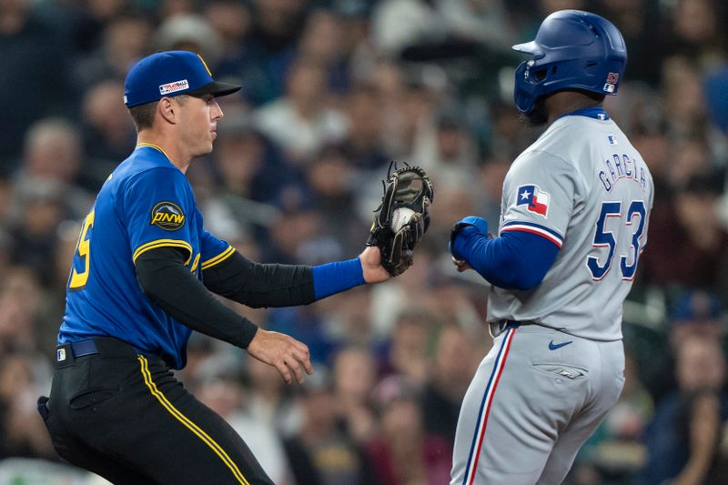 Jun 14, 2024; Seattle, Washington, USA; Seattle Mariners third baseman Dylan Moore (25) tags out Texas Rangers right fielder Adolis Garcia (53) during the sixth inning at T-Mobile Park. Mandatory Credit: Stephen Brashear-USA TODAY Sports