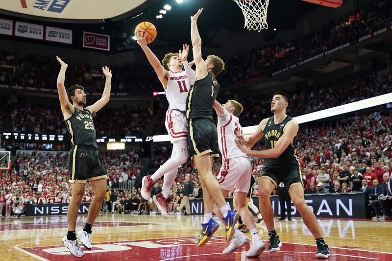 Mar 2, 2023; Madison, Wisconsin, USA; Wisconsin Badgers guard Max Klesmit (11) shoots the ball under coverage by Purdue Boilermakers forward Caleb Furst (1) and guard Ethan Morton (25) during the second half at the Kohl Center. Mandatory Credit: Kayla Wolf-USA TODAY Sports