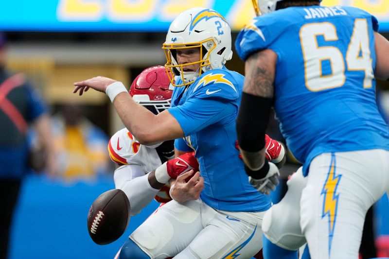 Los Angeles Chargers quarterback Easton Stick, center, fumbles the ball as he is sacked by Kansas City Chiefs defensive end Charles Omenihu, left, during the first half of an NFL football game, Sunday, Jan. 7, 2024, in Inglewood, Calif. The ball was recovered by Kansas City Chiefs safety Mike Edwards, before he ran it back for a touchdown on the play. (AP Photo/Ashley Landis)