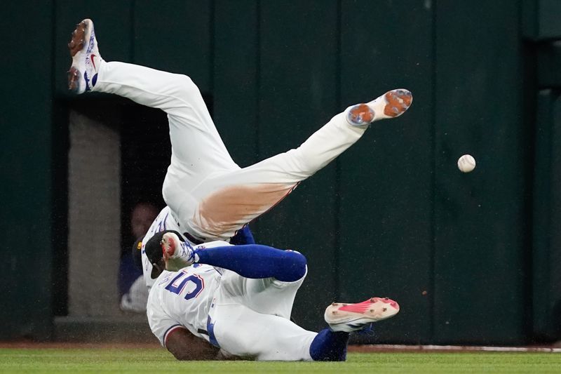 May 18, 2024; Arlington, Texas, USA; Texas Rangers second baseman Marcus Semien (2) collides with right fielder Adolis Garcia (53) chasing a fly ball during the sixth inning against the Los Angeles Angels at Globe Life Field. Mandatory Credit: Raymond Carlin III-USA TODAY Sports