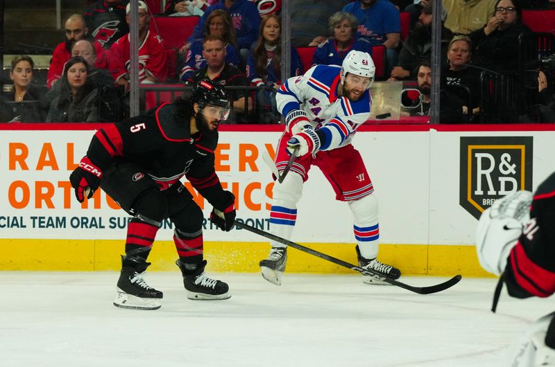Mar 12, 2024; Raleigh, North Carolina, USA; New York Rangers center Barclay Goodrow (21) takes a shot against Carolina Hurricanes defenseman Jalen Chatfield (5) during the second period at PNC Arena. Mandatory Credit: James Guillory-USA TODAY Sports