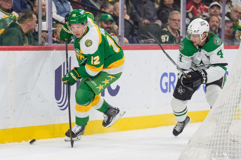 Dec 11, 2025; Saint Paul, Minnesota, USA; Minnesota Wild left wing Matt Boldy (12) secures the puck before Dallas Stars defenseman Miro Heiskanen (4) in the first period at Grand Casino Arena. Mandatory Credit: Matt Blewett-Imagn Images