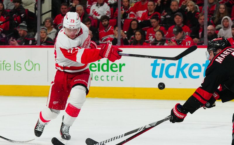 Jan 19, 2024; Raleigh, North Carolina, USA;  Detroit Red Wings left wing Lucas Raymond (23) takes a shot against the Carolina Hurricanes during the second period at PNC Arena. Mandatory Credit: James Guillory-USA TODAY Sports