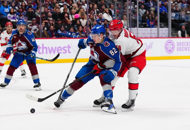 Nov 9, 2024; Denver, Colorado, USA; Carolina Hurricanes left wing Eric Robinson (50) and Colorado Avalanche center Ivan Ivan (82) battle for puck in the third period at Ball Arena. Mandatory Credit: Ron Chenoy-Imagn Images