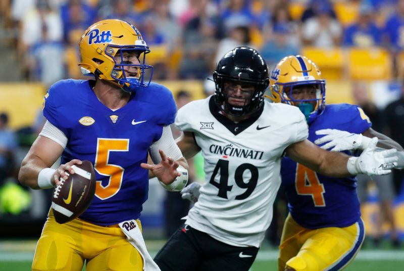 Sep 9, 2023; Pittsburgh, Pennsylvania, USA; Pittsburgh Panthers quarterback Phil Jurkovec (5) scrambles with the ball as Cincinnati Bearcats linebacker Jack Dingle (49) chases during the second quarter at Acrisure Stadium. Mandatory Credit: Charles LeClaire-USA TODAY Sports