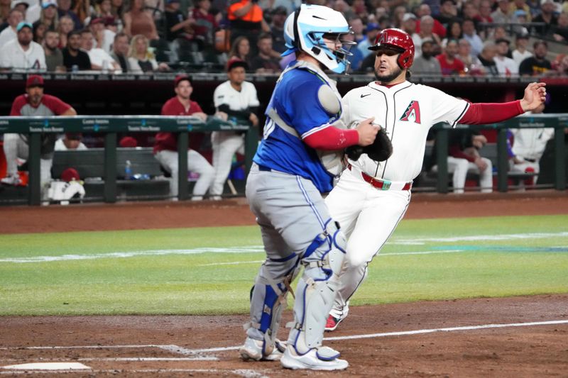 Jul 13, 2024; Phoenix, Arizona, USA; Arizona Diamondbacks third base Eugenio Suárez (28) slides in front of Toronto Blue Jays catcher Alejandro Kirk (30) to score a run during the third inning at Chase Field. Mandatory Credit: Joe Camporeale-USA TODAY Sports