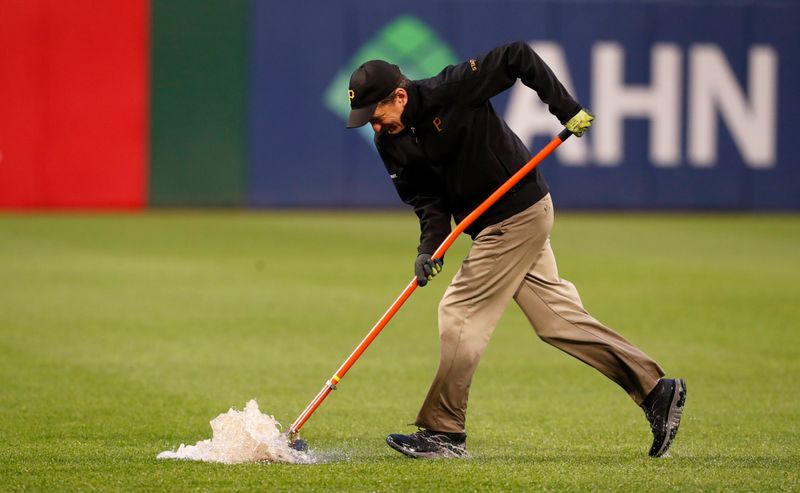 May 11, 2024; Pittsburgh, Pennsylvania, USA;  A member of the Pittsburgh Pirates grounds crew squeegees water in the outfield as play resumes during the fifth inning against the Chicago Cubs at PNC Park. Mandatory Credit: Charles LeClaire-USA TODAY Sports