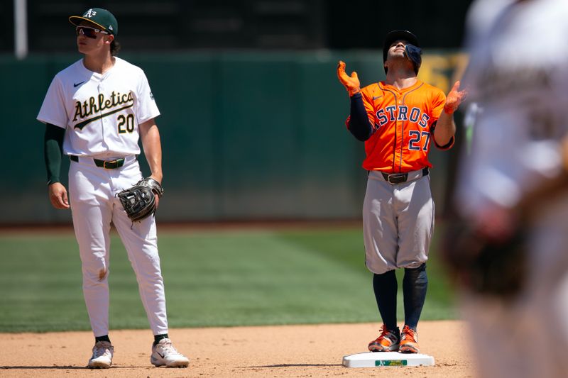 Jul 24, 2024; Oakland, California, USA; Houston Astros second baseman Jose Altuve (27) reacts after hitting a two-RBI double as Oakland Athletics second baseman Zack Gelof (20) looks on during the seventh inning at Oakland-Alameda County Coliseum. Mandatory Credit: D. Ross Cameron-USA TODAY Sports