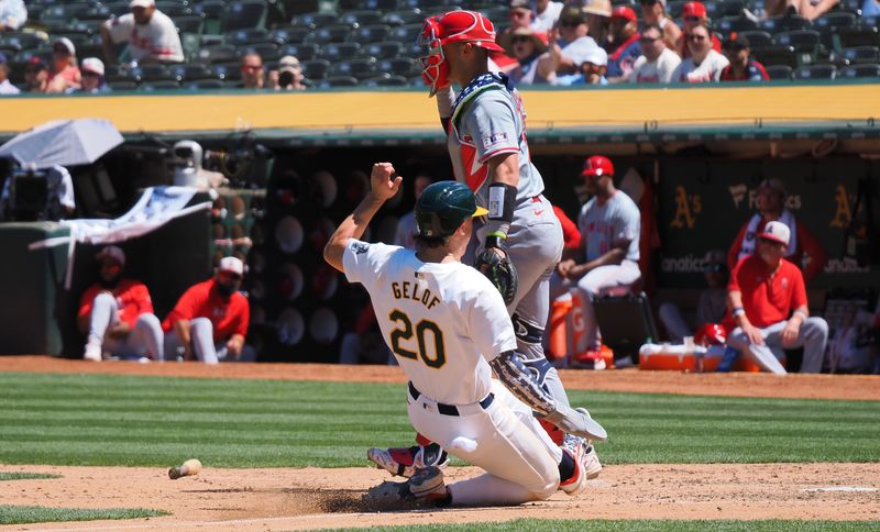 Jul 4, 2024; Oakland, California, USA; Oakland Athletics second baseman Zack Gelof (20) scores a run behind Los Angeles Angels catcher Logan O'Hoppe (14) during the sixth inning at Oakland-Alameda County Coliseum. Mandatory Credit: Kelley L Cox-USA TODAY Sports