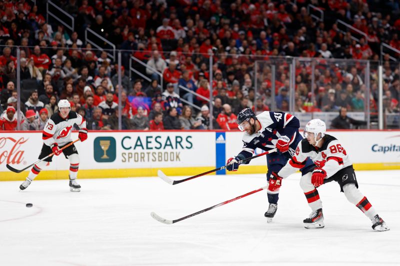 Feb 20, 2024; Washington, District of Columbia, USA; Washington Capitals right wing Tom Wilson (43) shoots the puck as New Jersey Devils center Jack Hughes (86) defends in the second period at Capital One Arena. Mandatory Credit: Geoff Burke-USA TODAY Sports