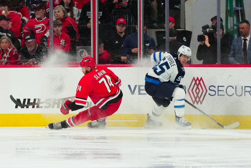 Mar 2, 2024; Raleigh, North Carolina, USA; Winnipeg Jets center Mark Scheifele (55) holds onto the puck against 
Carolina Hurricanes defense Jaccob Slavin (74) during the third period at PNC Arena. Mandatory Credit: James Guillory-USA TODAY Sports