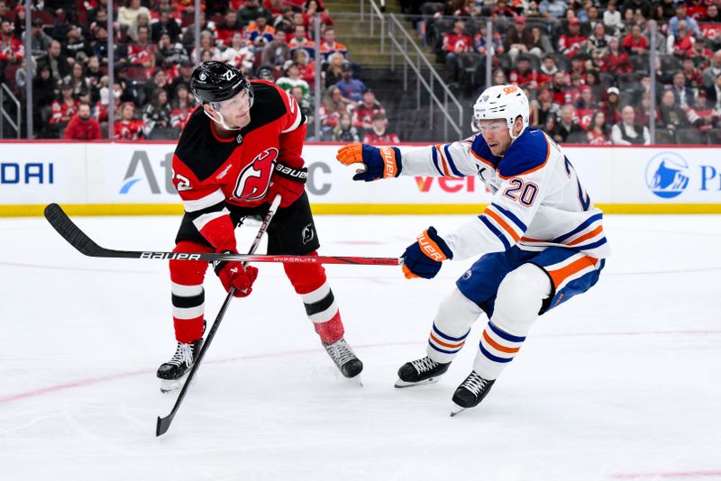 Oct 18, 2025; Newark, New Jersey, USA; New Jersey Devils defenseman Brett Pesce (22) passes the puck while defended by Edmonton Oilers center Curtis Lazar (20) during the first period at Prudential Center. Mandatory Credit: John Jones-Imagn Images