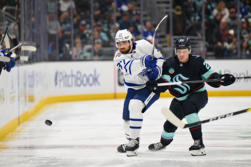 Jan 21, 2024; Seattle, Washington, USA; Toronto Maple Leafs defenseman Timothy Liljegren (37) clears the puck away from Seattle Kraken right wing Eeli Tolvanen (20) during the first period at Climate Pledge Arena. Mandatory Credit: Steven Bisig-USA TODAY Sports