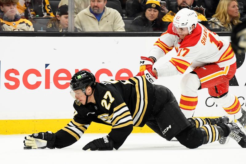 Feb 6, 2024; Boston, Massachusetts, USA; Boston Bruins defenseman Hampus Lindholm (27) swipes the puck away from Calgary Flames center Yegor Sharangovich (17) during the second period at TD Garden. Mandatory Credit: Bob DeChiara-USA TODAY Sports