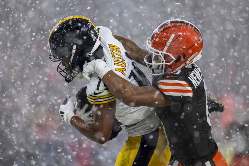 Pittsburgh Steelers wide receiver Calvin Austin III (19) catches a touchdown while being brought down by Cleveland Browns cornerback Greg Newsome II (0) during an NFL football game, Thursday, Nov. 21, 2024, in Cleveland. (AP Photo/Matt Durisko)